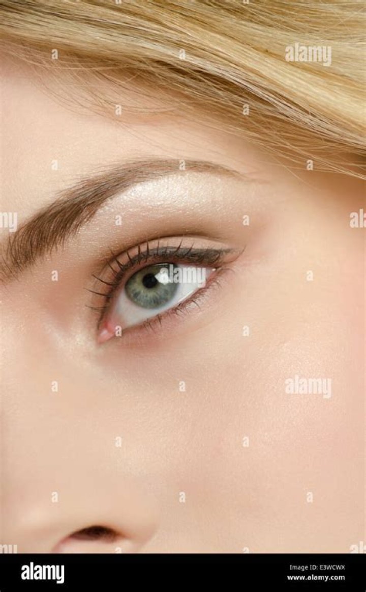 Close up of a beautiful young woman wearing makeup and jewelry accessories posing isolated over beige background