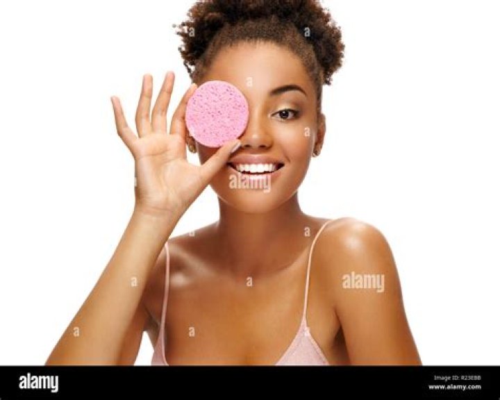 Funny girl holding pink sponge near her face. Portrait of young african american girl on white background. Youth and skin care concept; Shutterstock ID 1242539446; Comments: Art USe